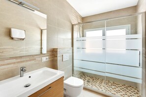 A modern bathroom with a glass shower enclosure, a white sink, and a toilet. - Villa Chispita (Fuengirola)