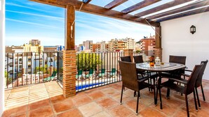 A terrace with a wooden pergola, outdoor seating, and a view of the cityscape. - Villa Chispita (Fuengirola)