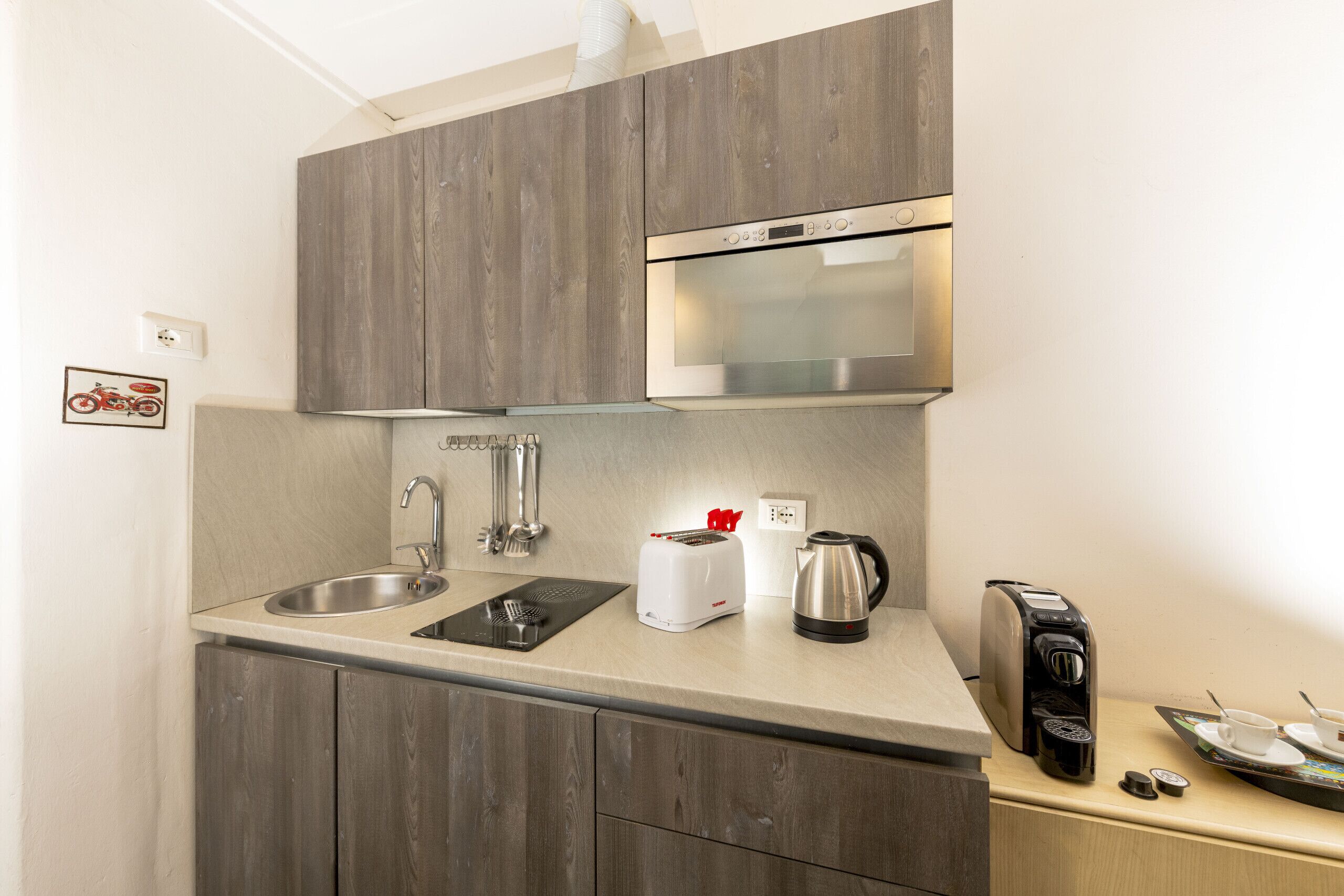 Eine Küchenzeile mit Edelstahlbackofen, Toaster, Wasserkocher und Kaffeemaschine.