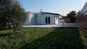 A modern single-story building with a flat roof, a small porch, and a clear sky.
