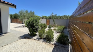 A courtyard with gravel ground, a wooden fence, and various shrubs.