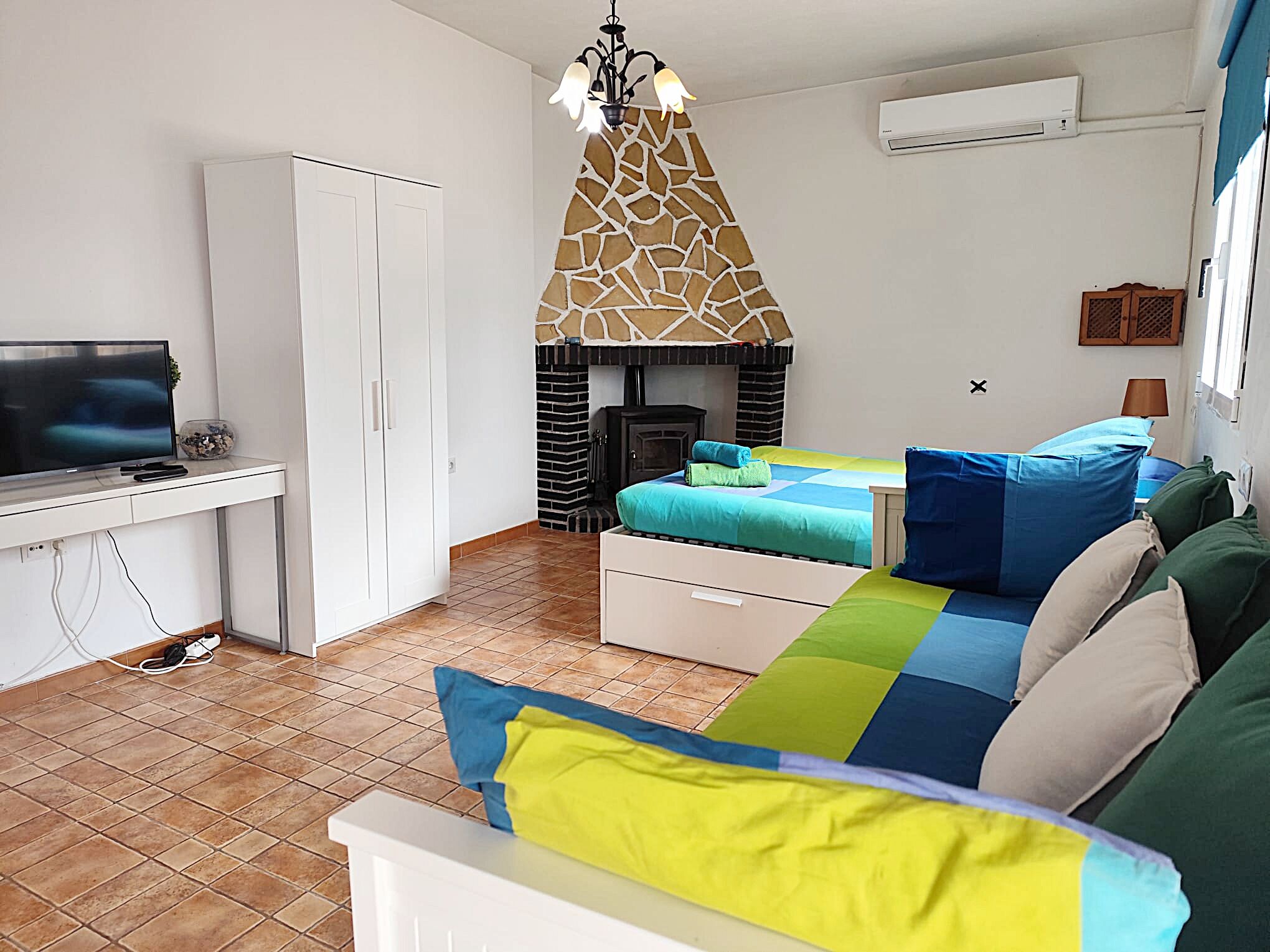 Een kamer met een bed, een bureau, een televisietoestel, een open haard en een airconditioning.