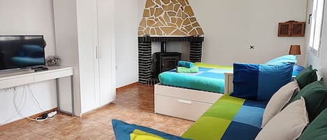 Une chambre comprenant un lit, un bureau, une télévision, une cheminée et un appareil de climatisation.