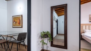 A room with a dining table, chairs, a potted plant, a large mirror, and a bed. - Light-filled Envigado, top-floor w/ Large Patio (Envigado)
