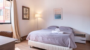 A bedroom with a wooden ceiling, a bed with a white headboard, a bedside table, a lamp, and a window with curtains. - Light-filled Envigado, top-floor w/ Large Patio (Envigado)