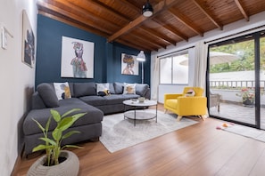 Un salon moderne avec un canapé gris, un fauteuil jaune et une table basse ronde.