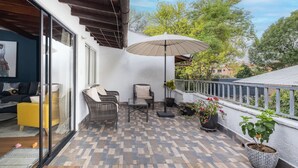 A balcony with a patterned floor, wicker furniture, a glass table, and a potted plant. - Light-filled Envigado, top-floor w/ Large Patio (Envigado)