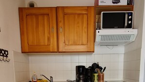 A compact kitchen with wooden cabinets, a microwave, a dishwasher, and a coffee maker. - Rental in the Mountain at Saint François LONGCHAMPS (Saint François LONGCHAMPS)