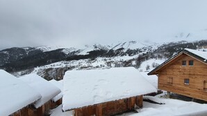 A wooden cabin with a snow-covered roof and a view of snow-covered mountains in the background. - Rental in the Mountain at Saint François LONGCHAMPS (Saint François LONGCHAMPS)