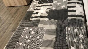 Quarto com cama, cabeceira, guarda-roupa de madeira e colcha estampada.