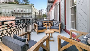 A balcony with wooden furniture, including sofas and a table, and a metal railing.