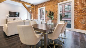 A dining area with a brick wall, a wooden ceiling, and a large window.
