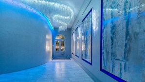 A hallway with a modern design, featuring a curved wall, a door at the end, and framed artwork on the walls.