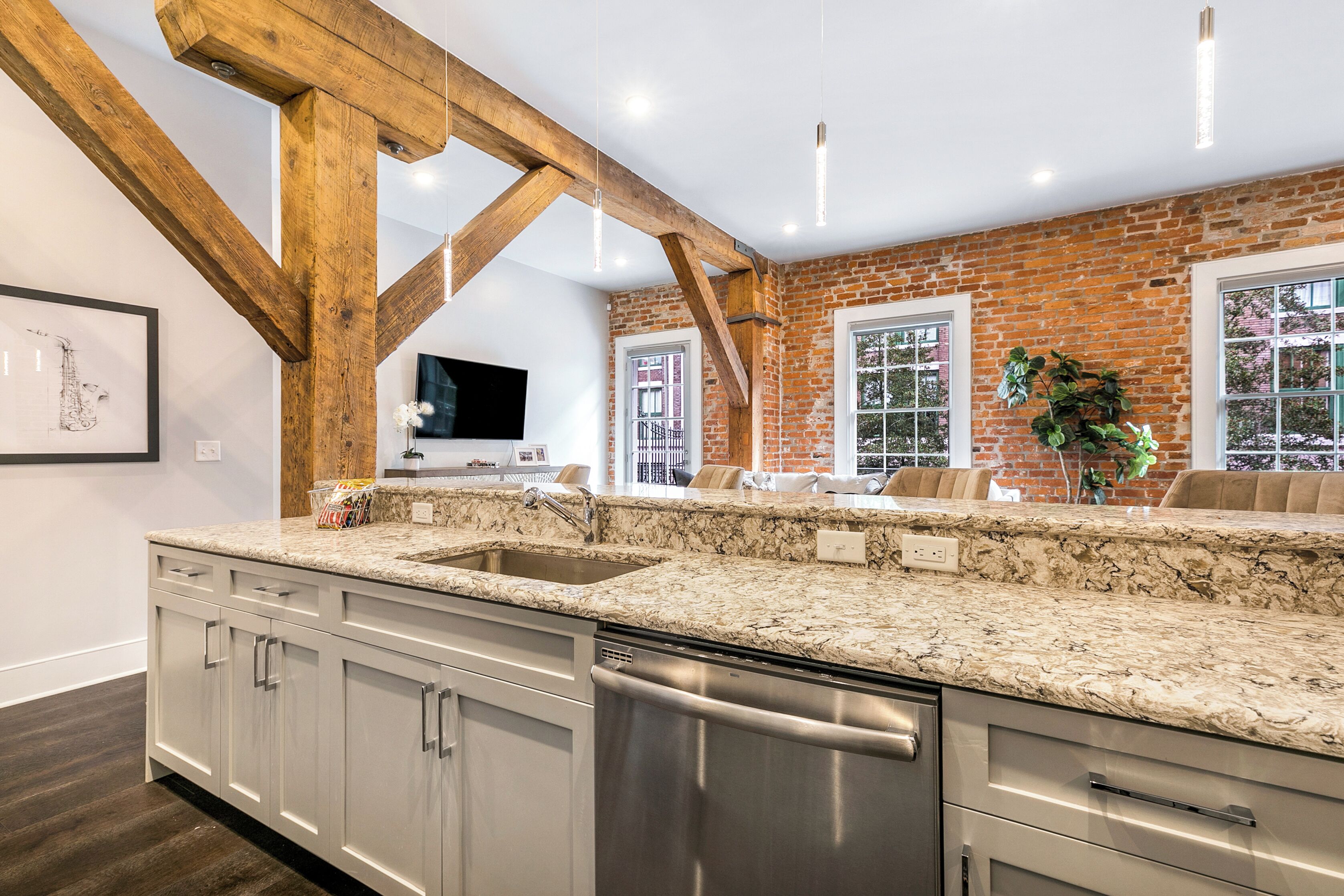 A kitchen with granite countertops, stainless steel appliances, and exposed wooden beams.