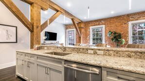 A kitchen with granite countertops, stainless steel appliances, and exposed wooden beams.