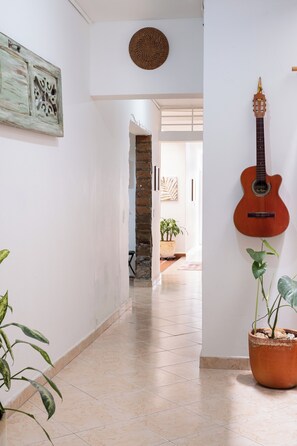 A hallway with a guitar wall art, a potted plant, and a textured ceiling. - Light filled, Envigado flat! Over 2000 square feet (Envigado)
