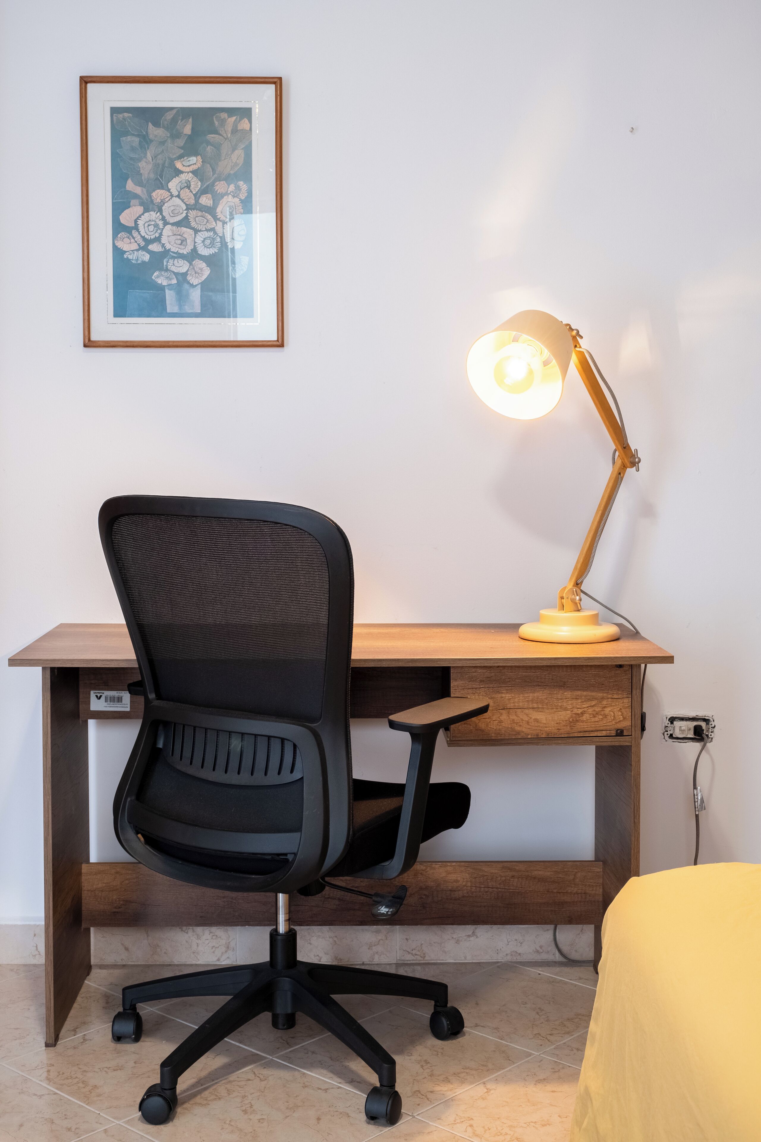 Ein Arbeitsplatz mit Schreibtisch, Bürostuhl und Schreibtischlampe.