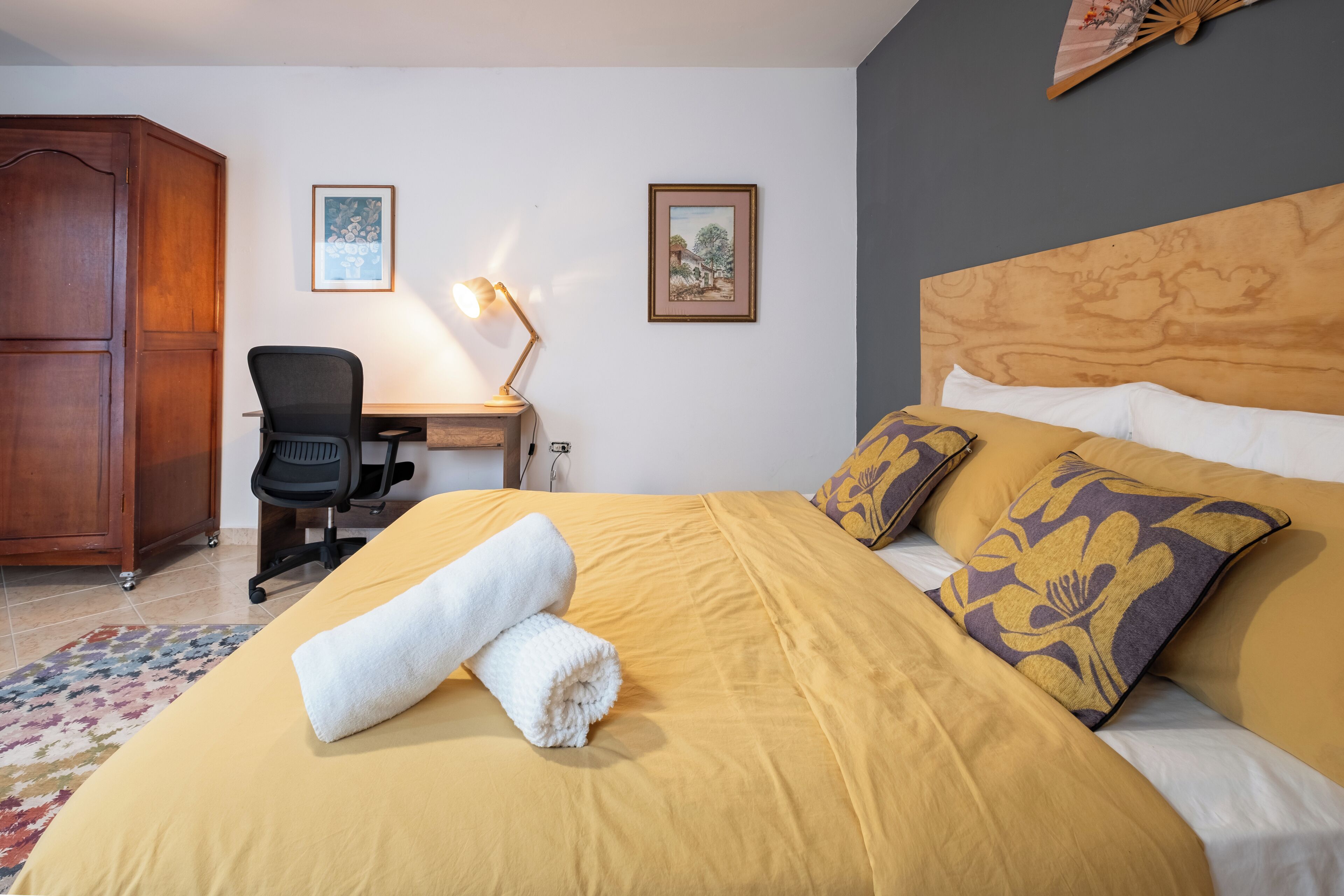 Een hotelkamer met een bed, bureau, stoel en kledingkast.