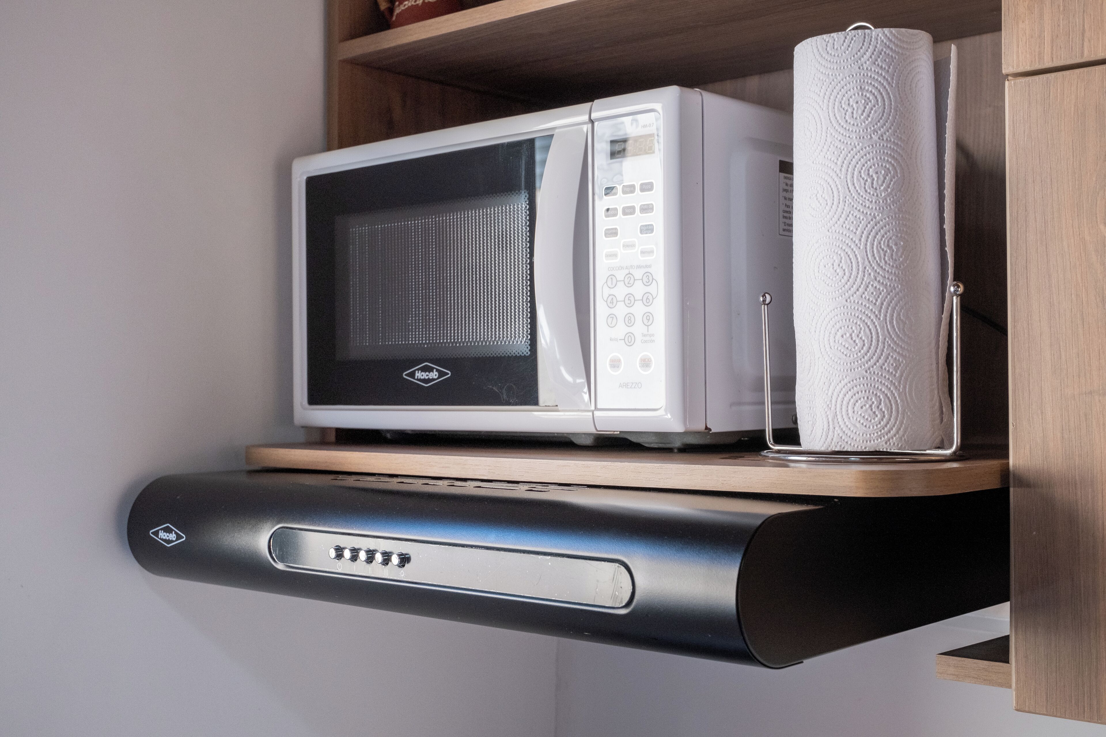 Un horno microondas sobre una repisa, con un rollo de papel de cocina al lado.