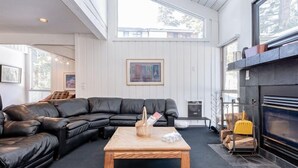 Un salón con un sofá seccional de cuero negro, una mesa de centro de madera y una chimenea.