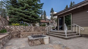 Un patio de piedra con un brasero, un muro de piedra y un edificio con porche cubierto.