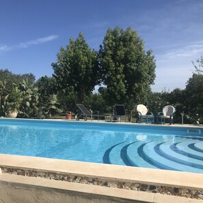 A swimming pool with lounge chairs and a solar-powered fan.