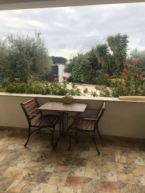 A patio with a table and chairs, surrounded by a garden with various plants and flowers.