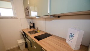 Een keuken met een houten aanrecht, een roestvrijstalen spoelbak en een koffiezetapparaat. Op het aanrecht staat een witte papieren zak met een logo.