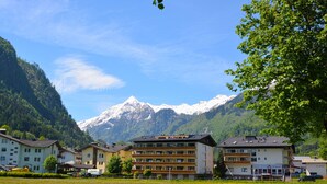 Een hotel met meerdere verdiepingen, balkons en een berg op de achtergrond.