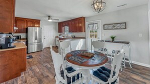 A modern kitchen with wooden cabinets, stainless steel appliances, and a dining area with white chairs and a wooden table. - Location! Location!<br>Minutes to all shopping and your favorites restaurant!  (Cullman)