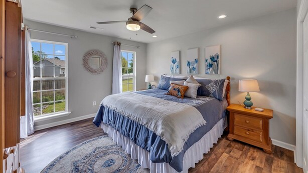 A bedroom with a large bed, a ceiling fan, a nightstand with a lamp, and a view of the outdoors through a window. - Location! Location!<br>Minutes to all shopping and your favorites restaurant!  (Cullman)