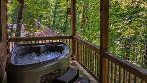 Un jacuzzi en una terraza de madera con vista a un bosque.