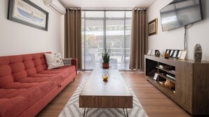 Un salon moderne avec un canapé rouge, une table basse en bois, un téléviseur et une bibliothèque.