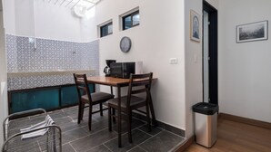 Une cuisine compacte comprenant une table à manger, des chaises, une machine à café et une poubelle.
