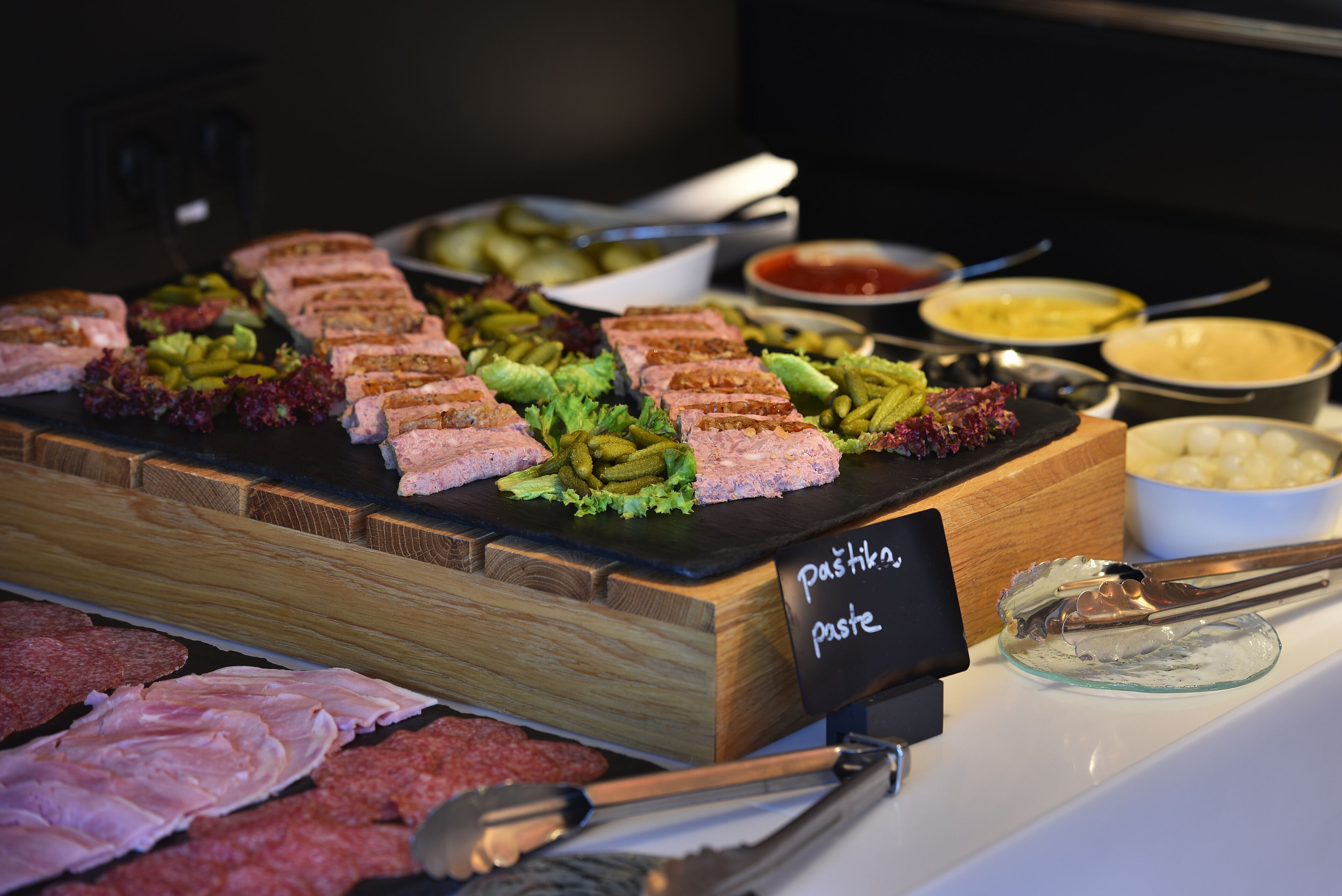 A buffet with various meats, pickles, and a sign indicating 'pastry paste'.