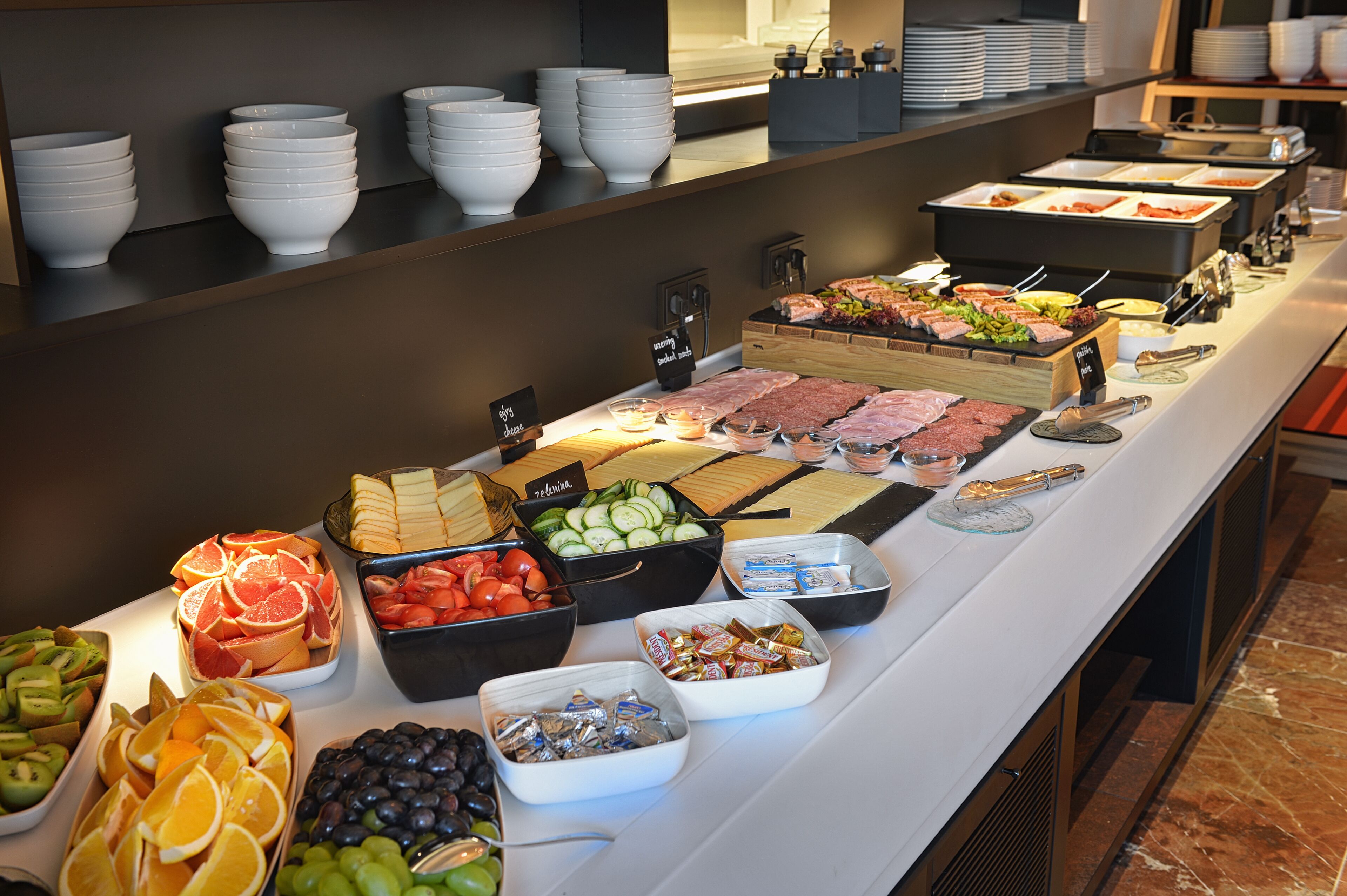 A buffet with various food items including fruits, meats, and cheeses.
