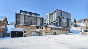 A modern building with large windows and a stone facade, featuring a shop named "Sportalm" on the ground floor.