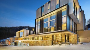 A modern hotel with a stone facade, large windows, and a flat roof. - Grand Hotel Hradec (Pec pod Snezkou)