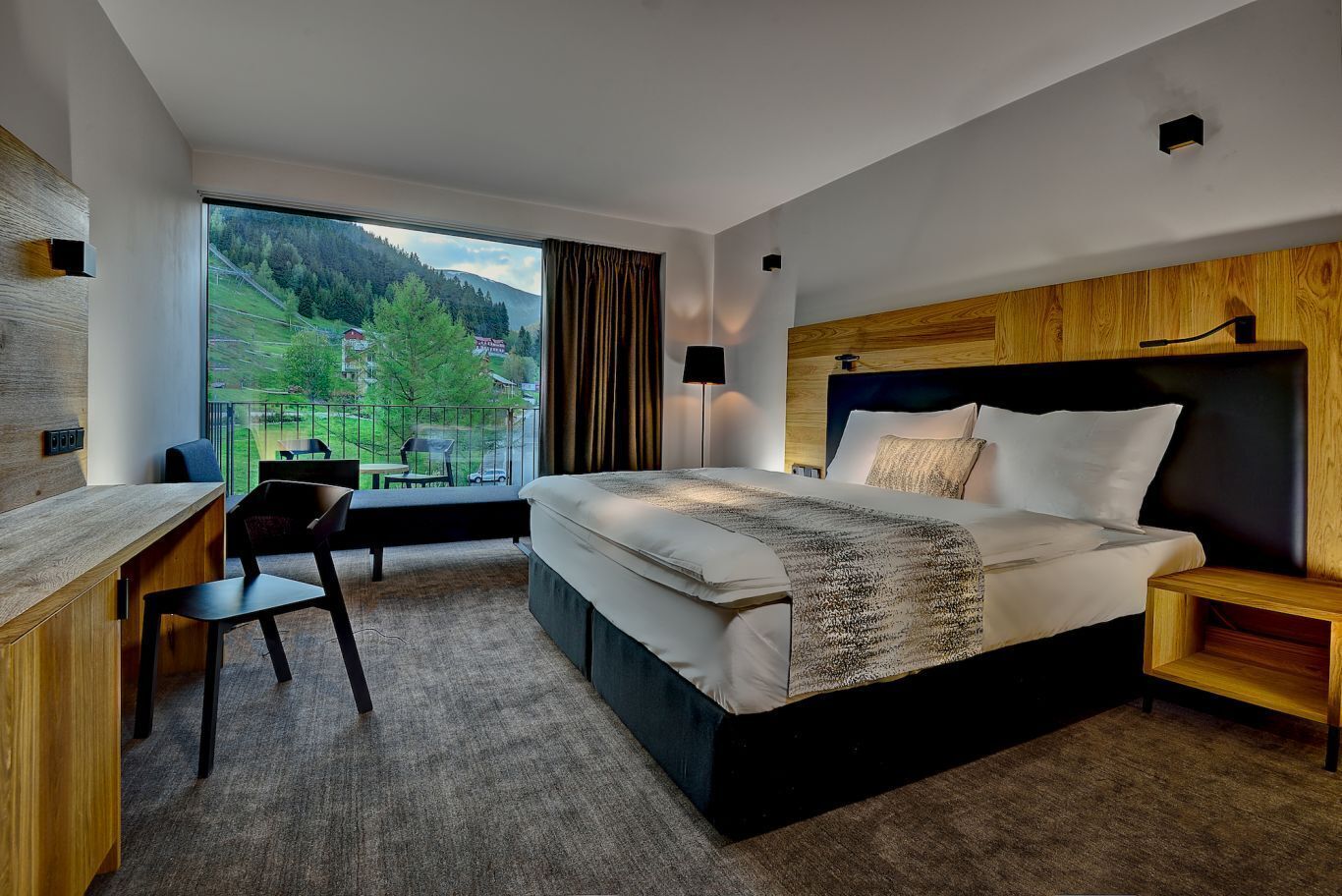 Ein modernes Hotelzimmer mit einem großen Bett, einem Schreibtisch und Blick ins Freie.