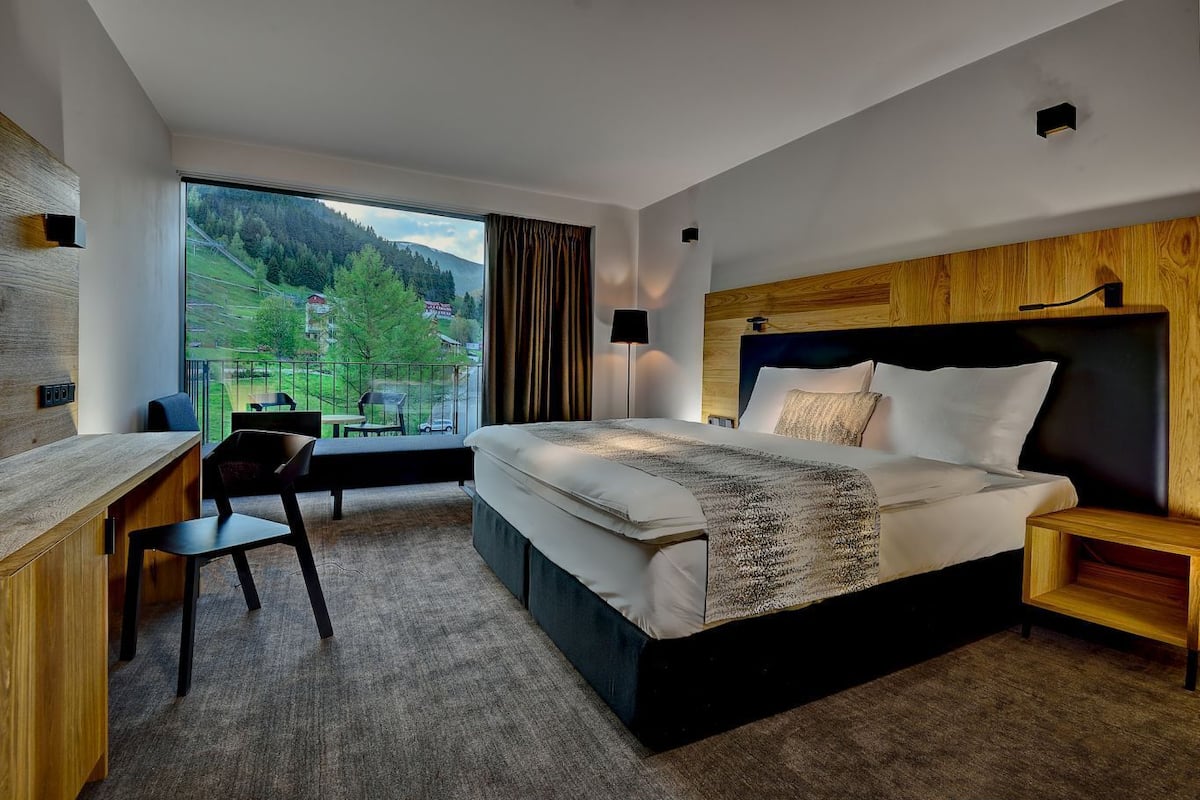 Ein modernes Hotelzimmer mit einem großen Bett, einem Schreibtisch und Blick ins Freie.