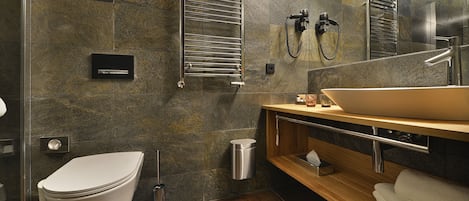Un baño moderno con inodoro blanco, un espejo grande, tocador de madera y lavamanos empotrado.