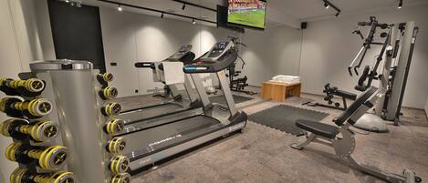 A gym with treadmills, dumbbells, and weight machines.