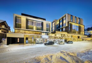 A modern building with a storefront labeled "SPORTAUM" and a parking area with snow. - Grand Hotel Hradec (Pec pod Snezkou)
