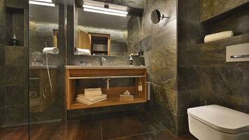 Un baño moderno con cabina de ducha de vidrio, tocador de madera y inodoro blanco.
