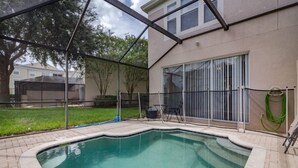A swimming pool with a covered area, a patio with chairs, and a hose. - Windsor_palms_2323n (Kissimmee)