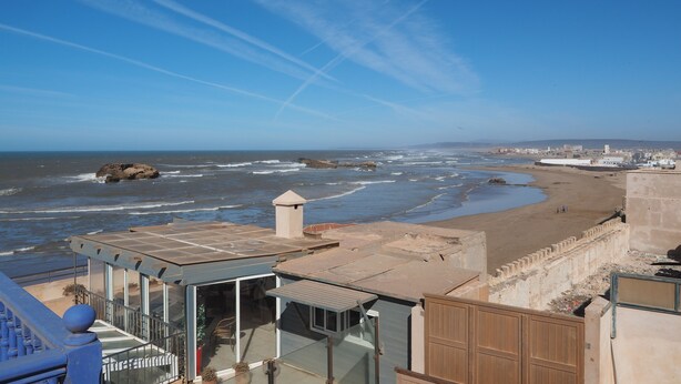 Une vue sur la côte, avec une plage, des vagues et un ciel dégagé.