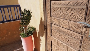 Une plante en pot placée à côté d’une porte ornée de sculptures complexes.