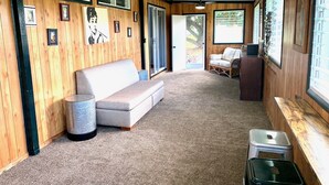 Um quarto aconchegante com parede de madeira, um sofá, uma mesa pequena e uma lixeira.