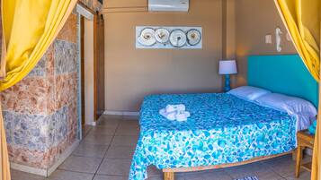 Una habitación con una cama, aire acondicionado instalado en la pared, un cuadro y una lámpara.