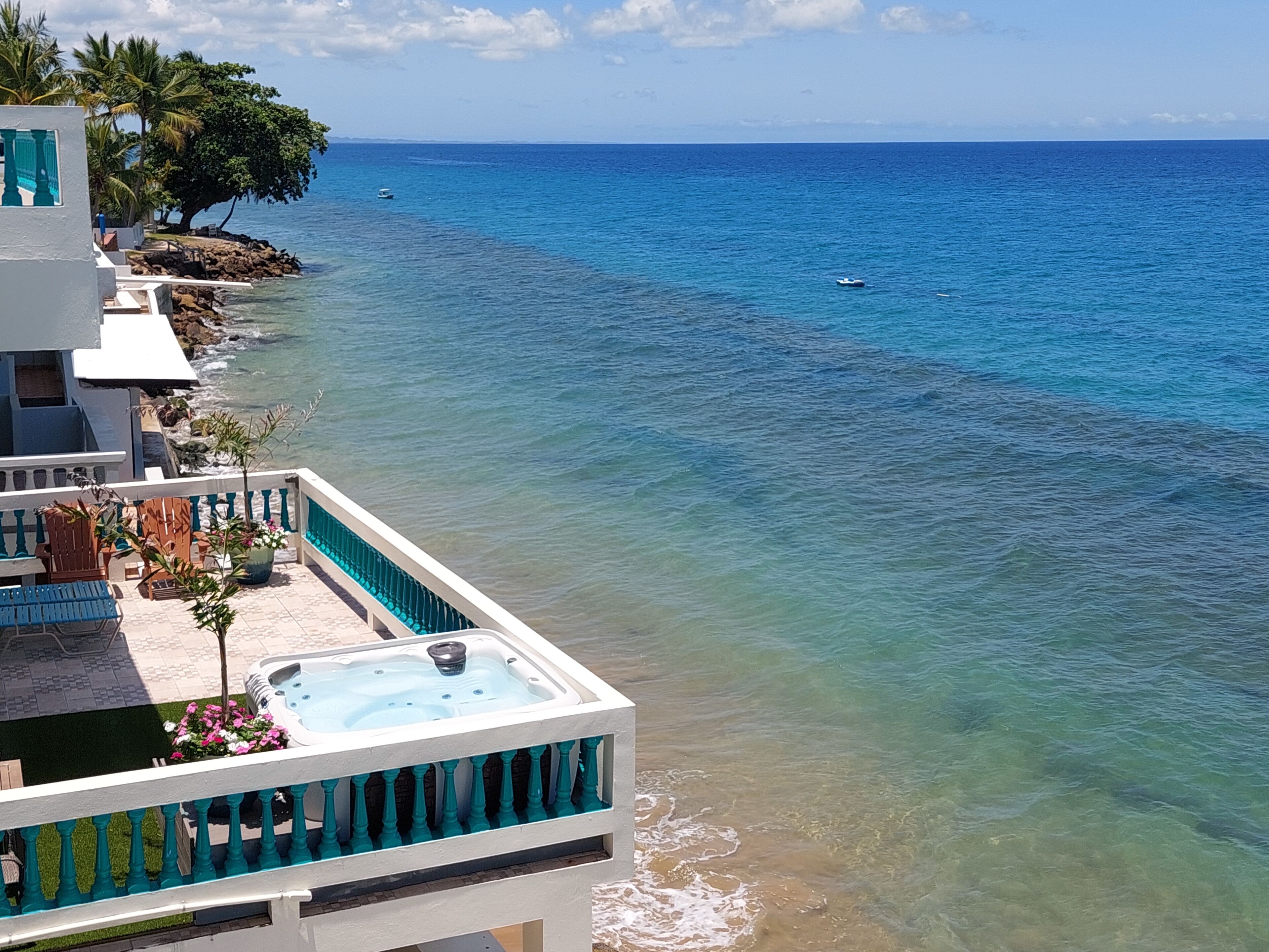 A balcony with a hot tub, seating, and a view of the ocean.